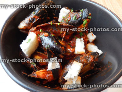 Stock image of seafood dish at restaurant, mussels, spicy tomato sauce, croutons