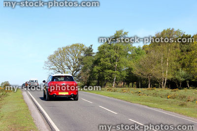 Stock image of convoy of minis, cars driving on road through New Forest