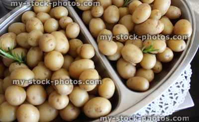 Stock image of freshly cooked new potatoes on silver platter, party food buffet