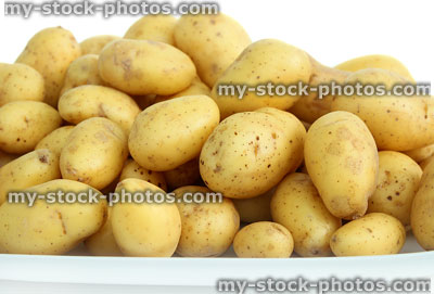 Stock image of new potatoes piled on white plate, waxy texture