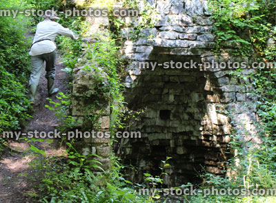 Stock image of old stone lime kiln in woodland, woman climbing