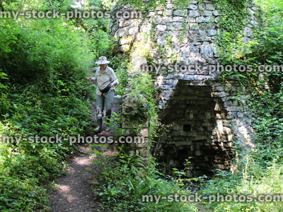 Stock image of old stone lime kiln in woodland, woman climbing