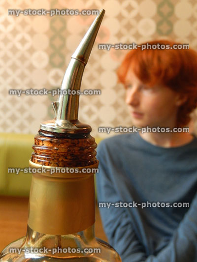 Stock image of olive oil bottle poured in restaurant, teenage boy in background