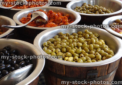 Stock image of barrels of stuffed olives sold at food market