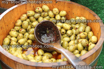 Stock image of wooden barrel of pitted green olives, farmer's market