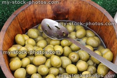 Stock image of wooden barrel of whole green olives, farmer's market