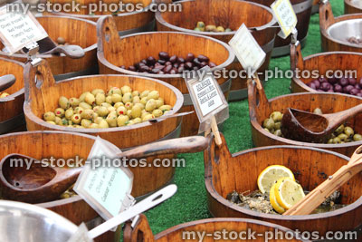 Stock image of wooden barrels of pitted green olives, farmer's market
