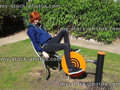 Stock image of boy exercising in fitness park, outdoor gym recumbent exercise bike
