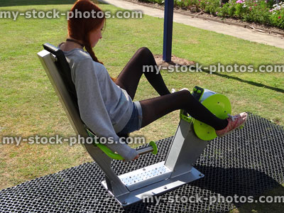 Stock image of girl sitting on recumbent exercise bike in fitness park
