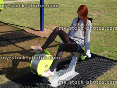 Stock image of girl exercising in fitness gym park on exercise bike / cycle 