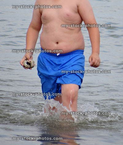 Stock image of overweight boy playing in sea
