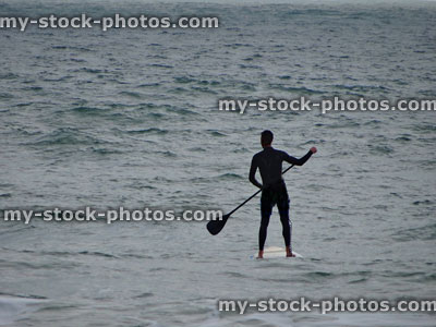 Stock image of surfer using paddle board / paddle boarded standing on surf board
