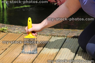 Stock image of wooden timber decking lengths in garden being painted