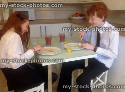 Stock image of children eating pancake breakfast in modern white kitchen