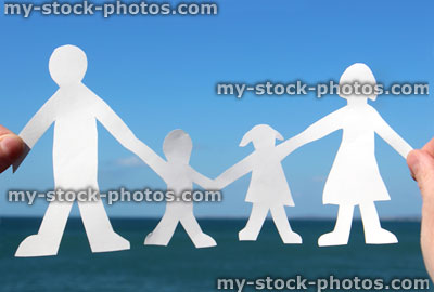 Stock image of people family paper chain held against sea / sky