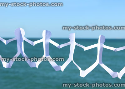 Stock image of white paperchain people with sea / sky background