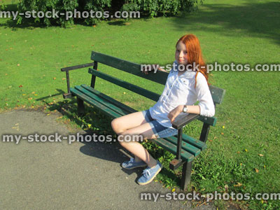 Stock image of girl sitting on bench painted green, garden / park