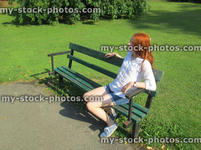 Stock image of girl sitting on park bench painted green, garden