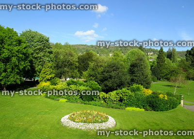 Stock image of park with expanse of green lawn grass, trees and flowers