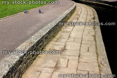 Stock image of stream, with paved footpath, lawn grass and pigeons