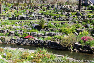 Stock image of planted rock garden (rockery) with flowers and stream