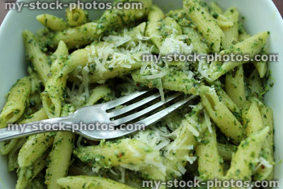 Stock image of pesto pasta in white dish, grated parmesan cheese