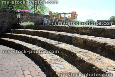 Stock image of outside table and chairs, curved stone steps and block paving