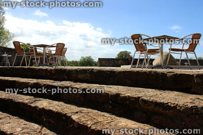 Stock image of wicker garden table and chairs, stone steps and block paving
