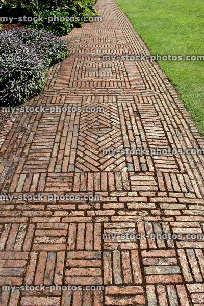 Stock image of red brick path, block paving, paved pathway, basketweave / diamond pattern, lawn
