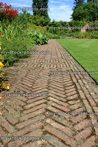 Stock image of red brick path, block paving, paved pathway, herringbone pattern / lawn