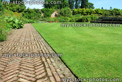 Stock image of red brick path, block paving, paved pathway, herringbone pattern, lawn
