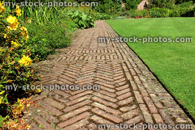 Stock image of red brick path, block paving, paved pathway, herringbone pattern, lawn