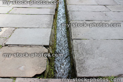Stock image of small stream / rill running down centre of flagstone paved street