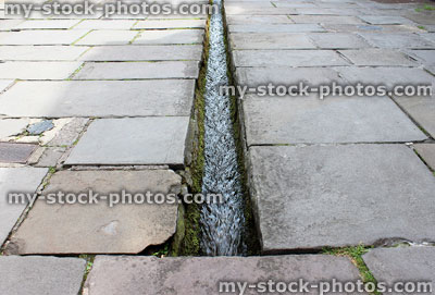 Stock image of small stream / rill running down centre of flagstone paved street