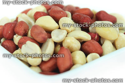 Stock image of redskin peanuts pile in white dish, healthy eating snack food