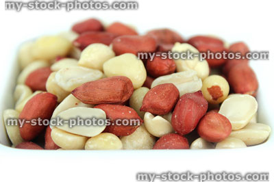 Stock image of mixed red skin peanuts in white dish, healthy snack