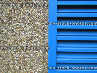 Stock image of roughcast / pebbledash, wall texture background, blue louvre door, plaster cement render