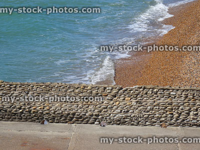 Stock image of seaside pebble wall with paving pathway, drainage holes