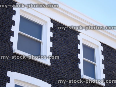 Stock image of house exterior facade of black pebbles, white windows