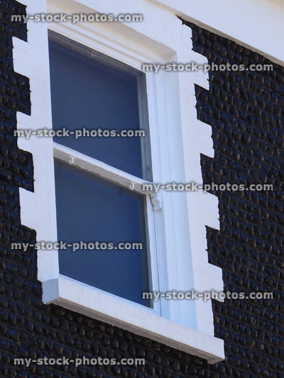 Stock image of white sash window with black pebble house exterior