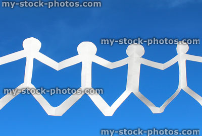 Stock image of four paperchain people in row, holding hands, blue sky