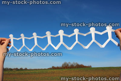 Stock image of white people paper chain of dolls, men holding hands, blue sky