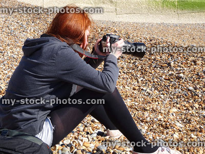 Stock image of girl taking beach photos with her SLR camera