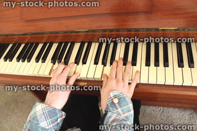 Stock image of teenage boy playing the piano, wooden piano keyboard