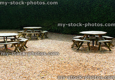 Stock image of round wooden picnic tables in garden, on gravel