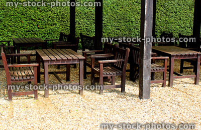 Stock image of wooden garden table, chairs and benches on gravel 