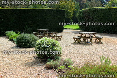 Stock image of round wooden picnic tables in ornamental gravel garden
