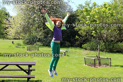 Stock image of girl jumping off picnic table onto garden lawn