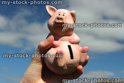 Stock image of cheerful smiling pink piggy bank held in hand 