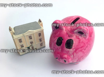 Stock image of pink piggy bank and tiny dolls house